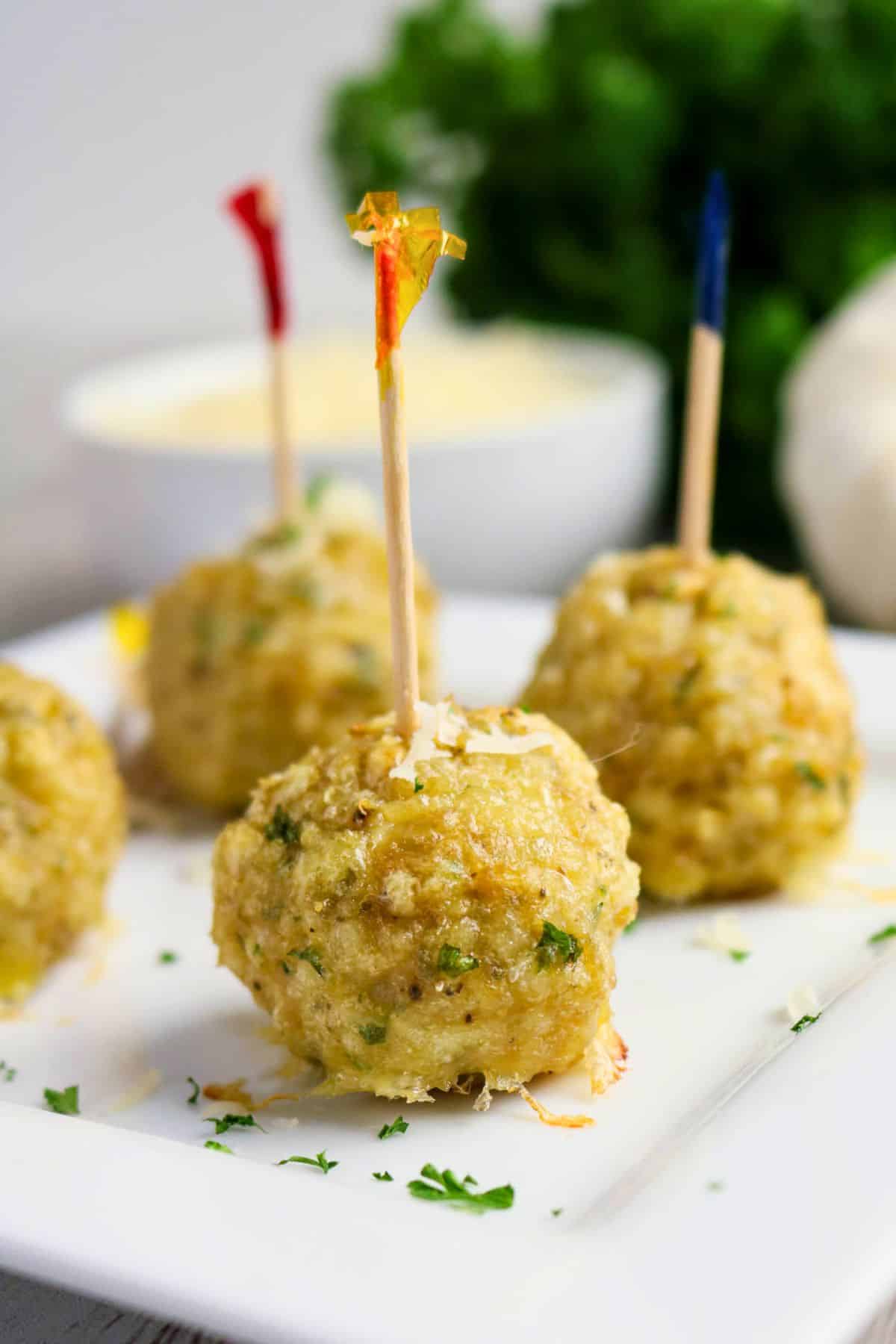 Baked Chicken Parmesan meatballs served with toothpicks on a white platter.