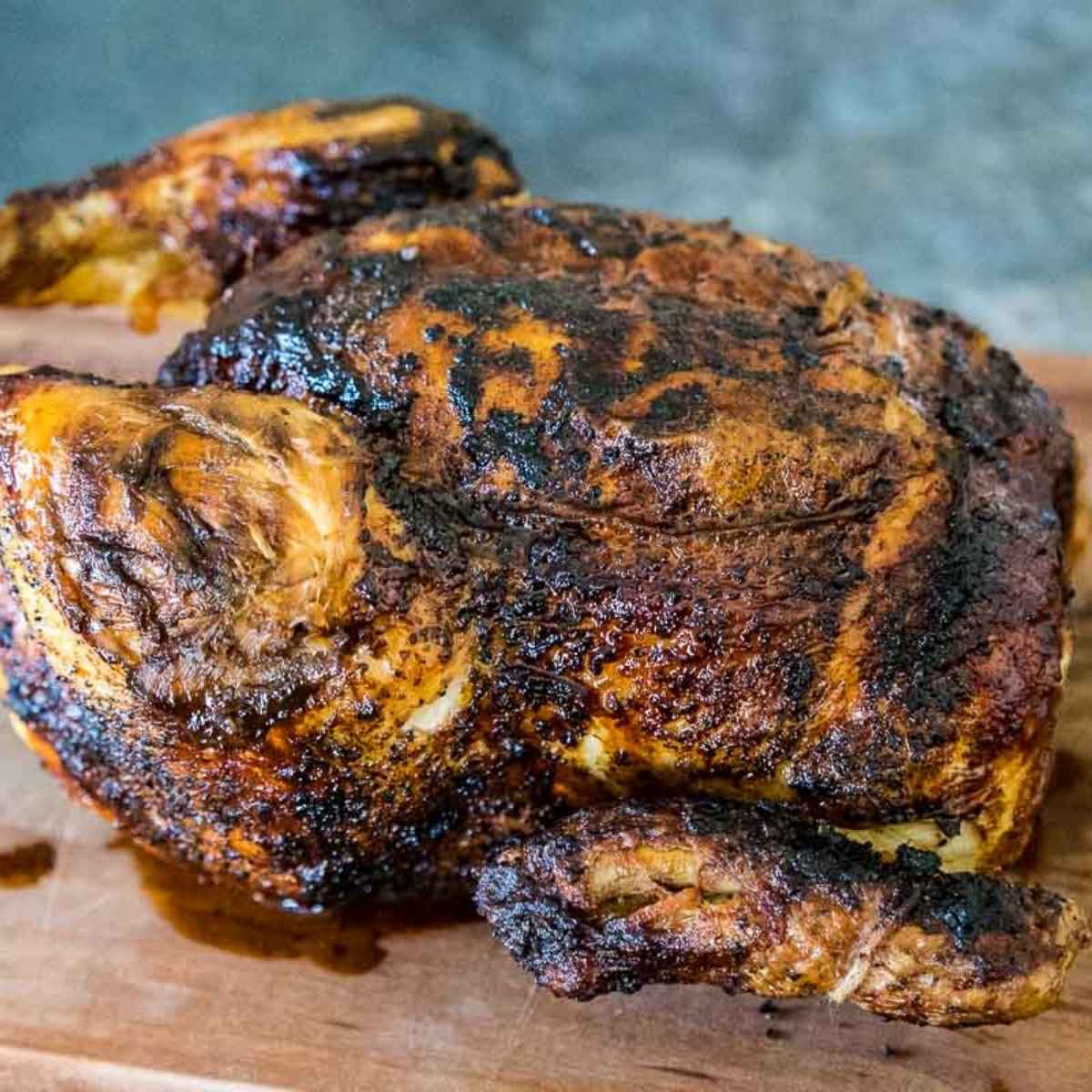 Air Fryer Rotisserie Chicken on a wooden cutting board with spit and twine removed.