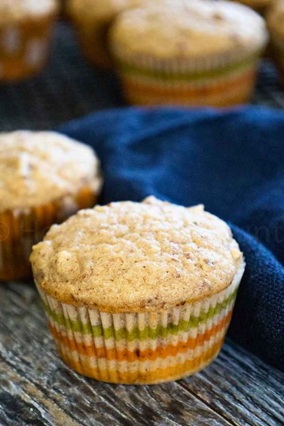 Applesauce Muffins on a wooden tray with a dark blue napkin at the side.