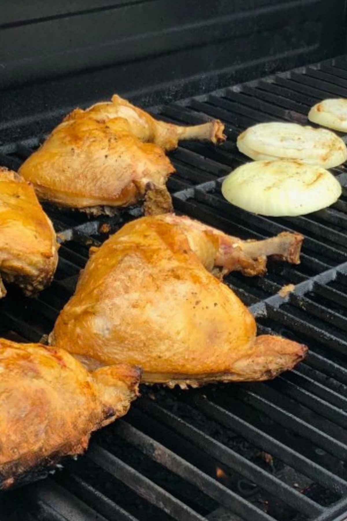 Golden brown grilled chicken leg quarters and onion rings on an electric grill.