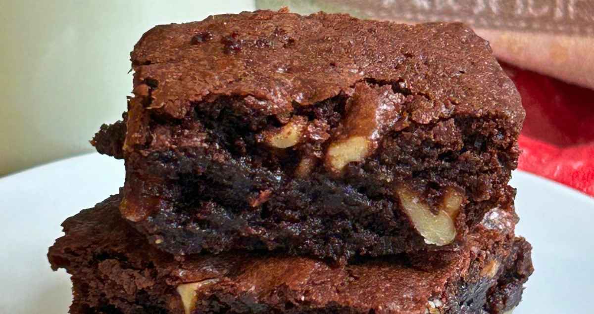 Upclose image of Nanny's Walnut Brownies stacked by two and on a white plate.