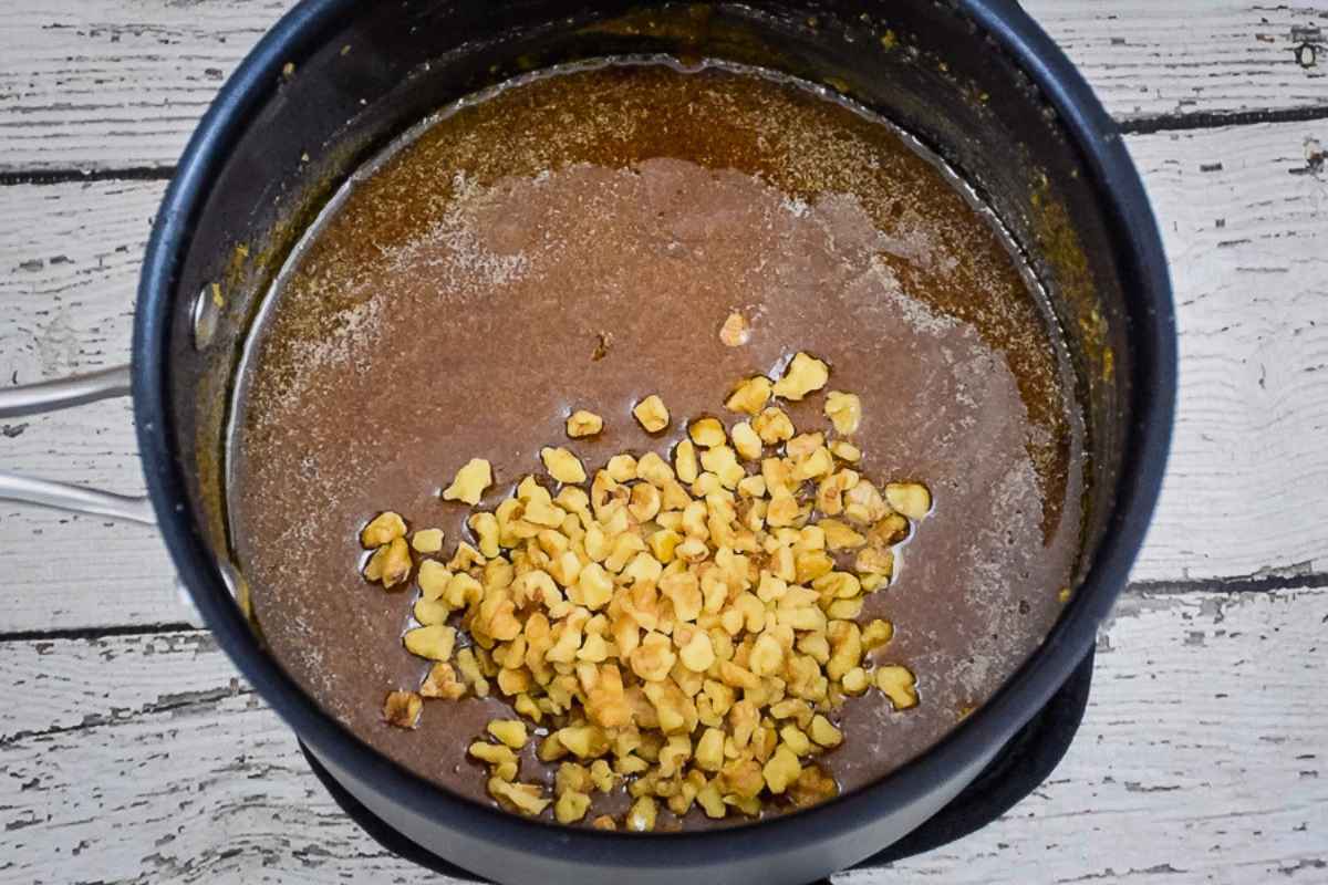 Adding walnuts to Brown Sugar Fudge in pot before stirring.