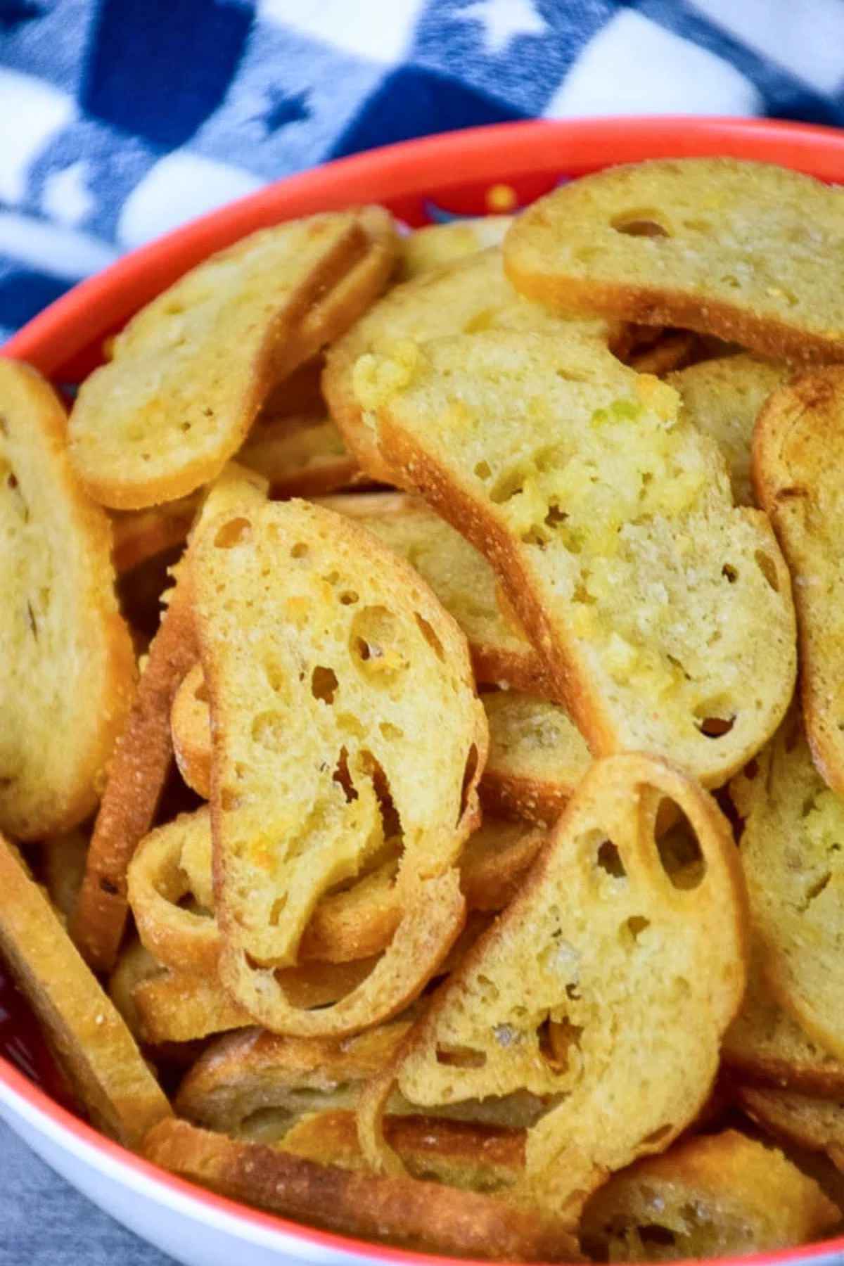 An upclose image of a bowl full of golden brown crispy buttery garlic bread chips.