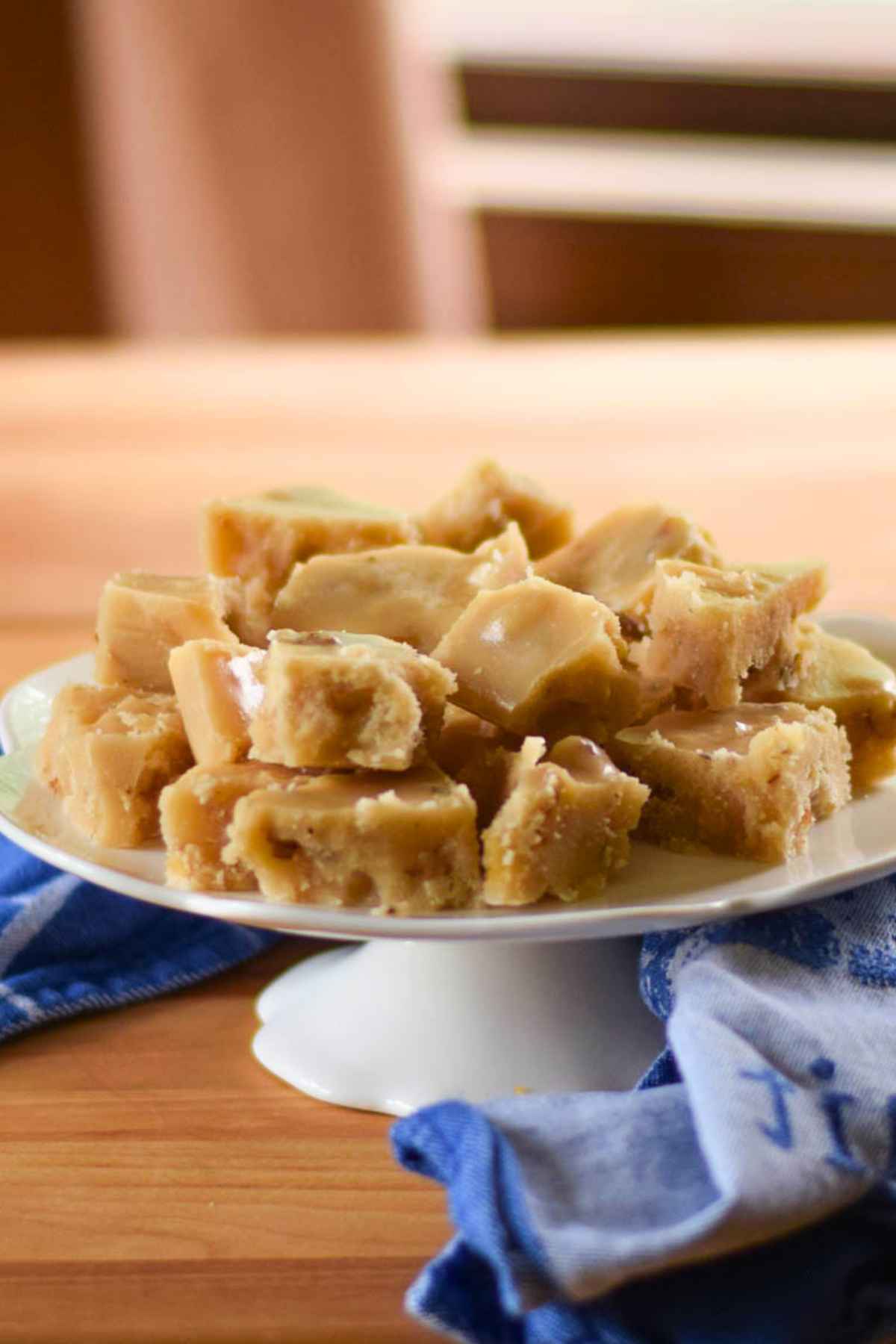 A white pedestal plate stacked with pieces of with maple candy.