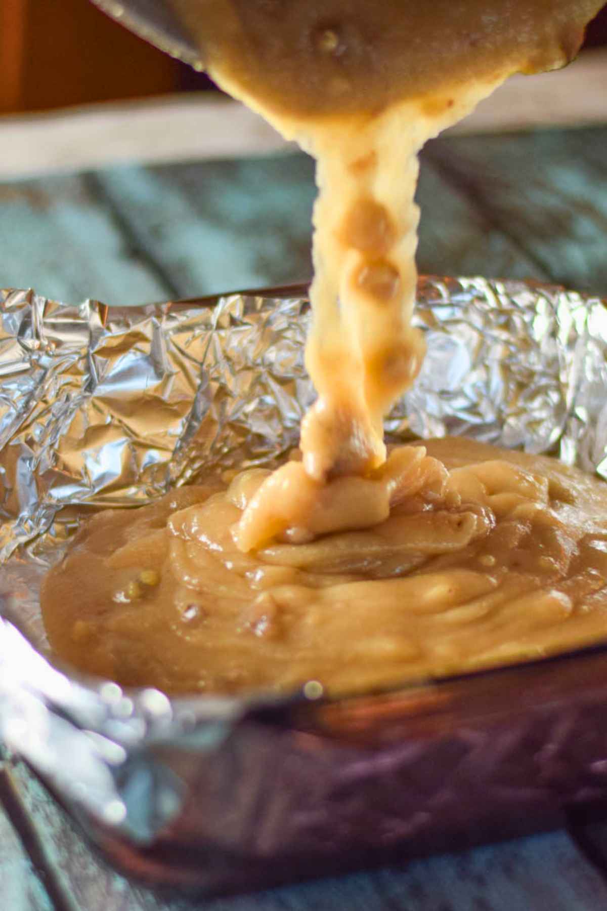 Pouring cooked maple fudge into pan lined with foil.
