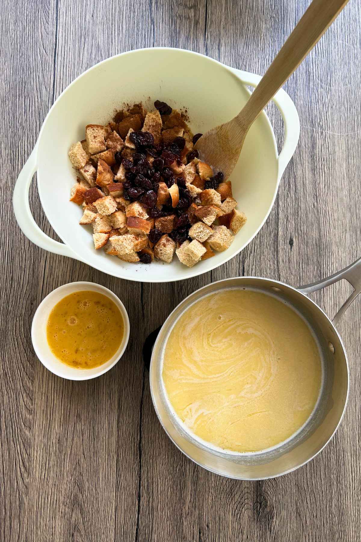An overhead view of a large white bowl filled with cubed bread and raisins,
