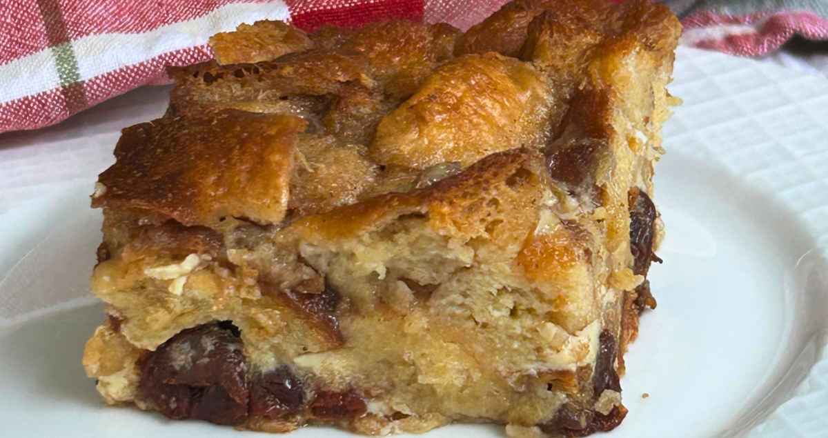 Upclose image of Mom's Old Fashioned Bread Pudding on a white plate with a red and white checkered napkin in the background.