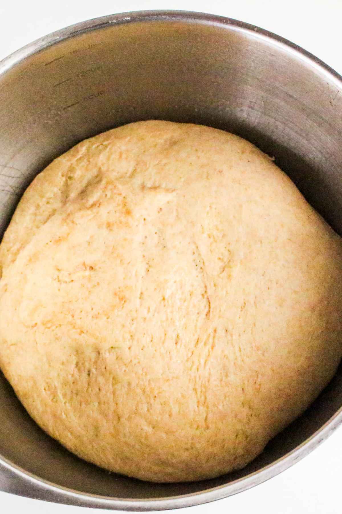 Overhead of dough on it's first rise in a stainless steel bowl.