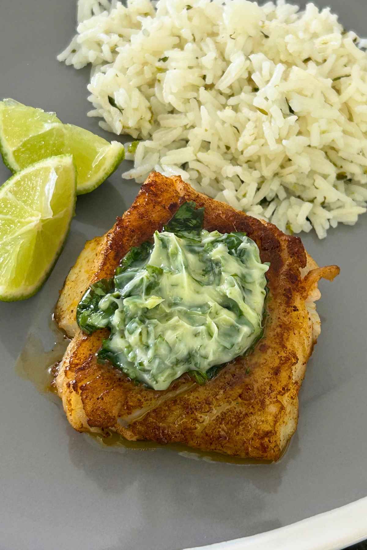 Overhead image of Pan-Seared Cod Fish with Cilantro Lime Butter topping and a side of rice and two lime wedges.