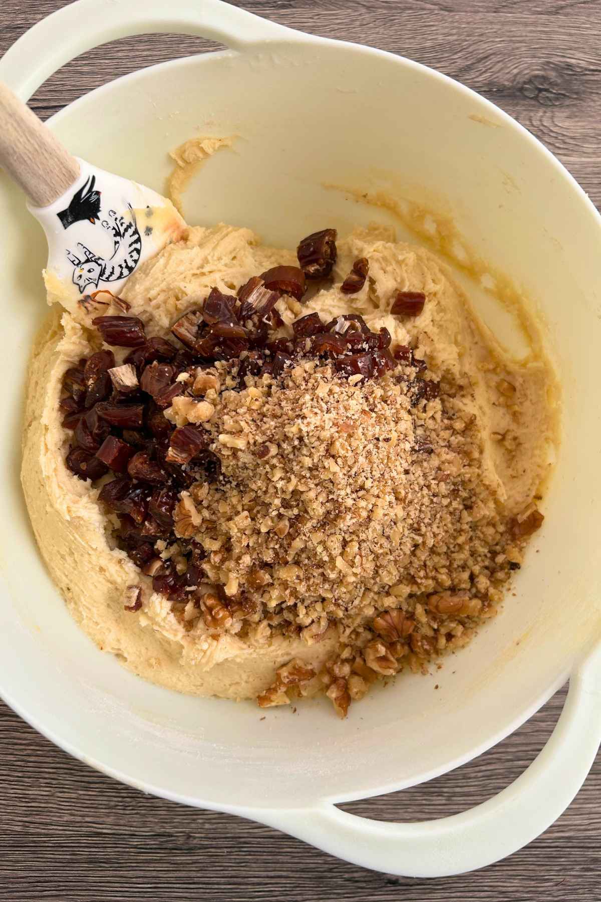 A large bowl with cookie dough topped with chopped dates and nuts.