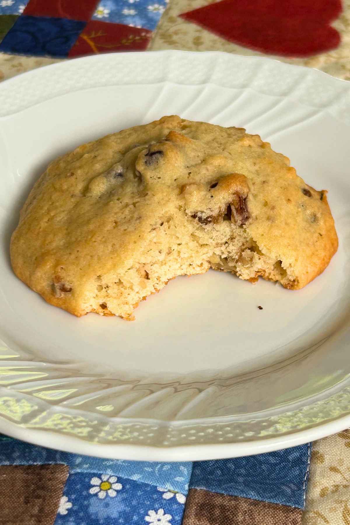 One cookie on a white plate with a bite taken out of it.
