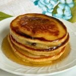 Upcloase shot of a stack of pancakes with syrup over top.