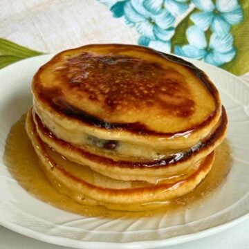 Upcloase shot of a stack of pancakes with syrup over top.