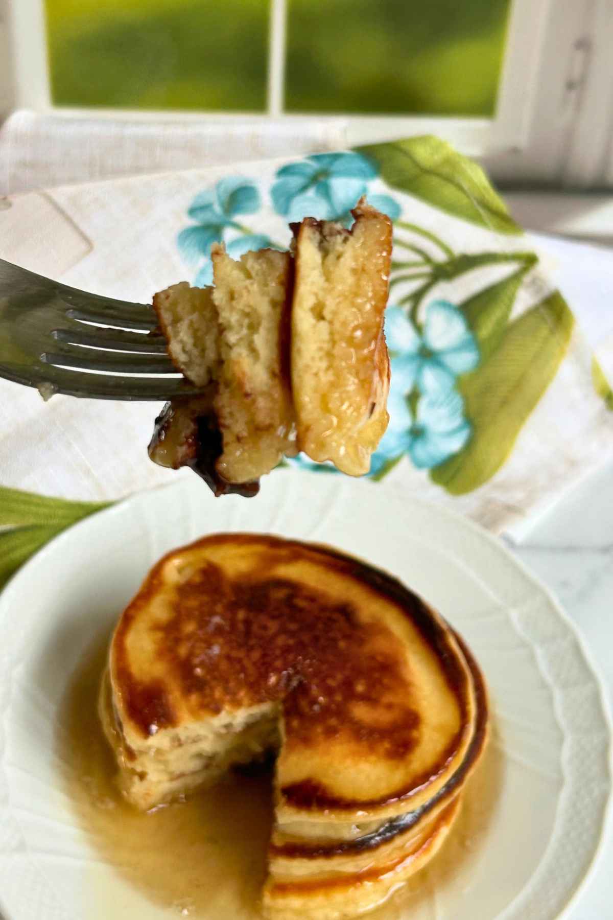 Bite shot of pancakes with syrup on a fork.